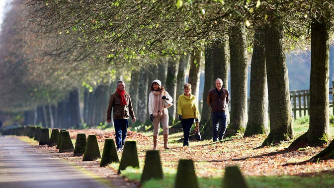 Four people walking along the driveway at Heythrop Park in winter casual wear