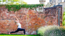 Woman in yoga pose in front of brick wall
